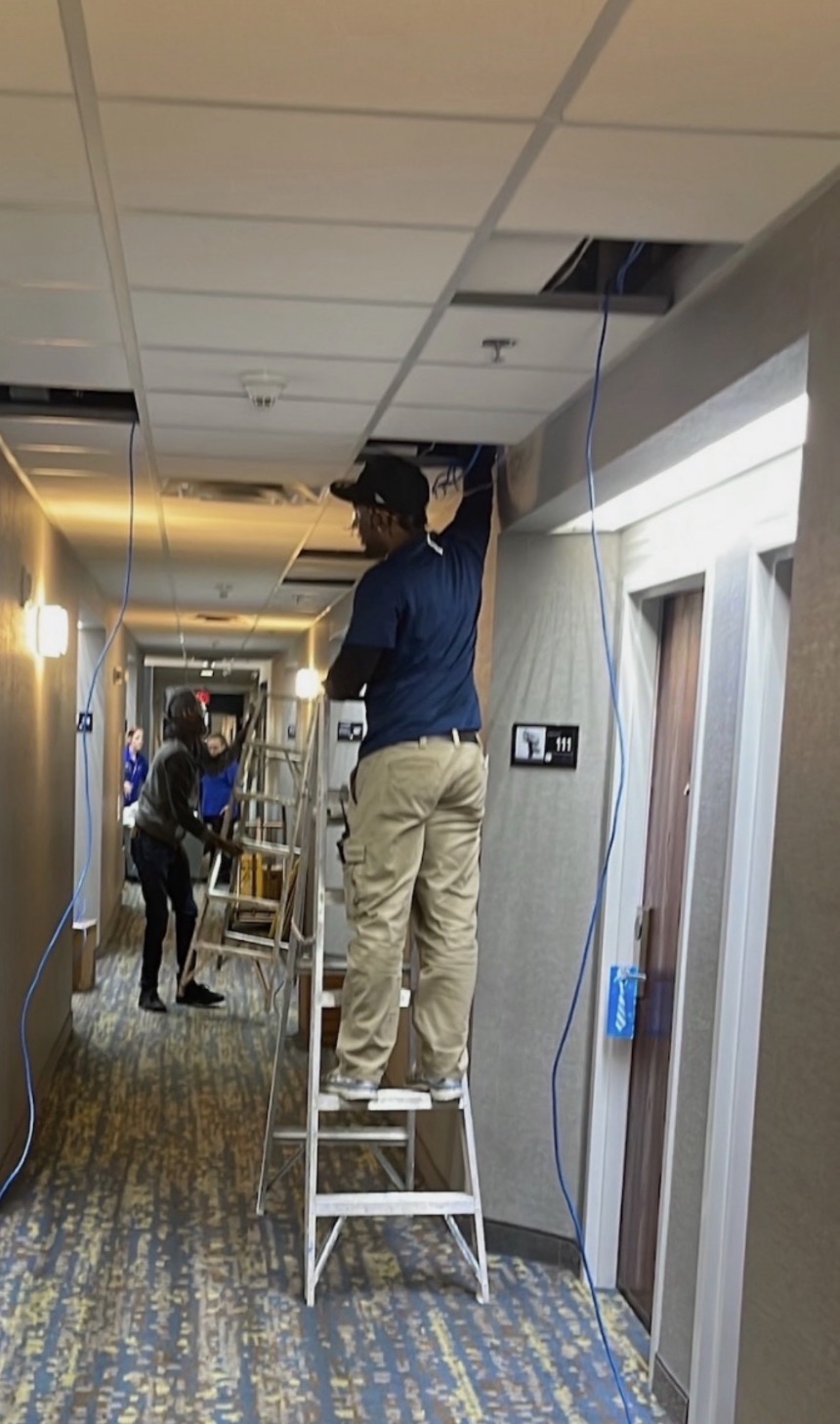 Technician installing ceiling cabling on a ladder